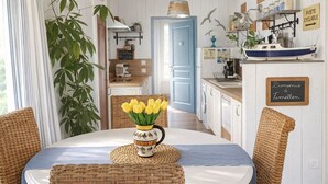 A dining area with a table set for four, a vase of yellow flowers, and wicker chairs. - Romantic cottage with private heated pool - 2 pers - Bassin d'Arcachon (Lanton)