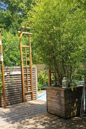 A wooden deck with a bamboo plant and a lantern.