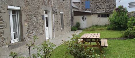 A stone building with a wooden table in the yard.
