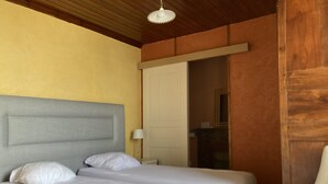 Ein Zimmer mit zwei Betten, Holzboden, einer weißen Tür und einem Spiegel.