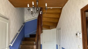 Eine Treppe mit Holzbalken und einem blauen Geländer, die zu einer weißen Tür führt.
