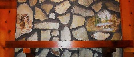 A stone wall with a painting of an owl and a landscape.