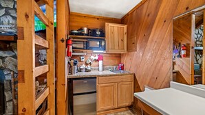Una cocina compacta con armarios de madera, un refrigerador de acero inoxidable, un microondas y un lavamanos.