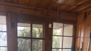 A wooden cabin with a large door and windows, a mop, a bucket, and a radiator. - LAVENDER  LIZARD B Upper Unit CASITAS (Farmington)