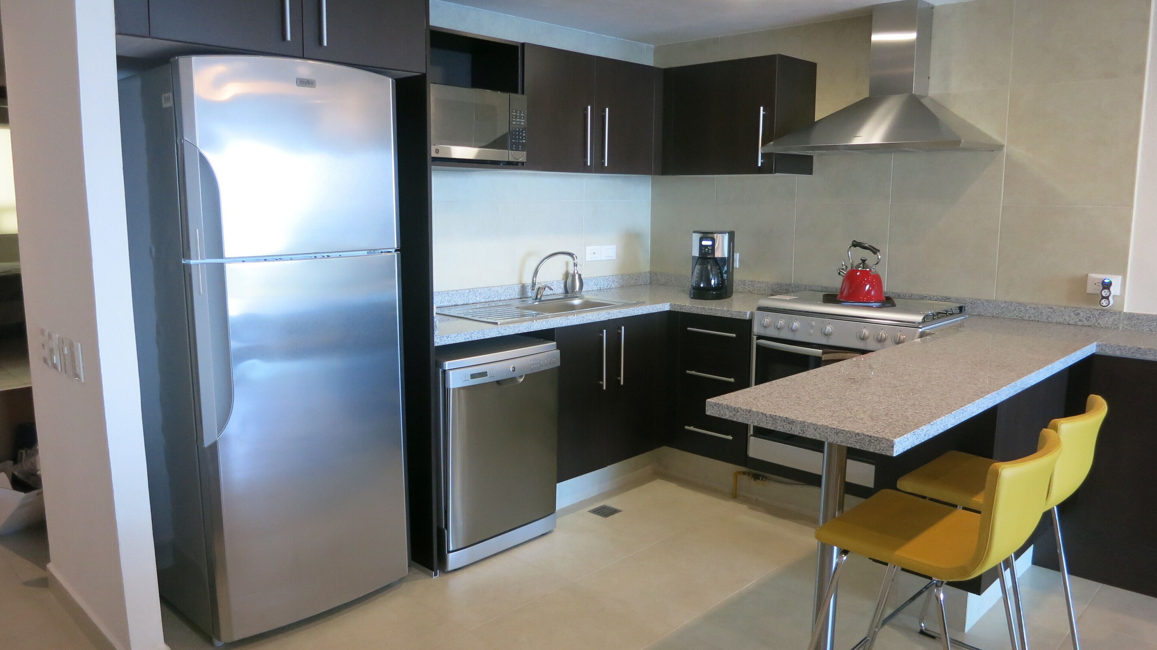 A modern kitchen with stainless steel appliances, a coffee maker, and a kettle.