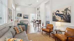 Un salon spacieux comprenant un canapé, des fauteuils, un coin repas et un grand tableau accroché au mur.