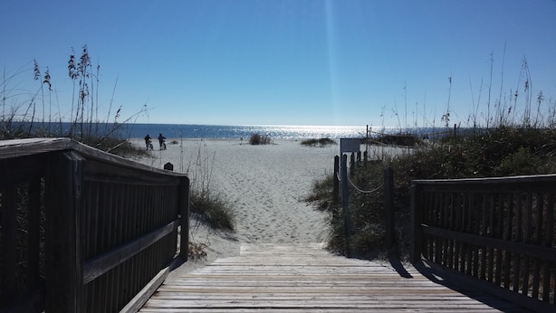 A wooden boardwalk leading to a beach with people on bicycles. - Adorably furnished and updated Ocean Villa condo, with wonderful 200+ Reviews! (Hilton Head Island)
