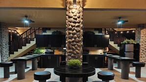 A modern kitchen with black cabinets, a central island, and a stone accent wall.