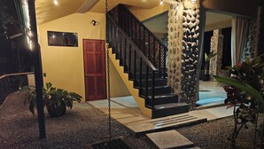 A modern staircase with a stone wall, a red door, and a hanging light fixture.