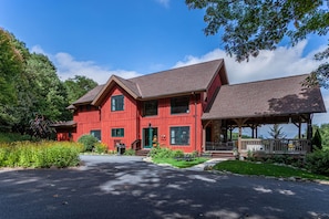 A red two-story house with a covered porch and a driveway.