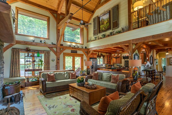 A spacious living area with high ceilings, wooden beams, and large windows.