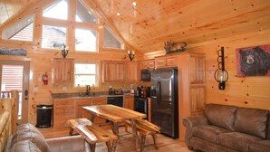 A wooden cabin interior with a kitchen, dining area, and seating. - Luxury 4 King Suites, 4 Bath Log Cabin Close to Town & Trolley (Gatlinburg)