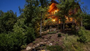 A log cabin with a stone pathway leading to a waterfall, surrounded by dense forest. - Luxury 4 King Suites, 4 Bath Log Cabin Close to Town & Trolley (Gatlinburg)