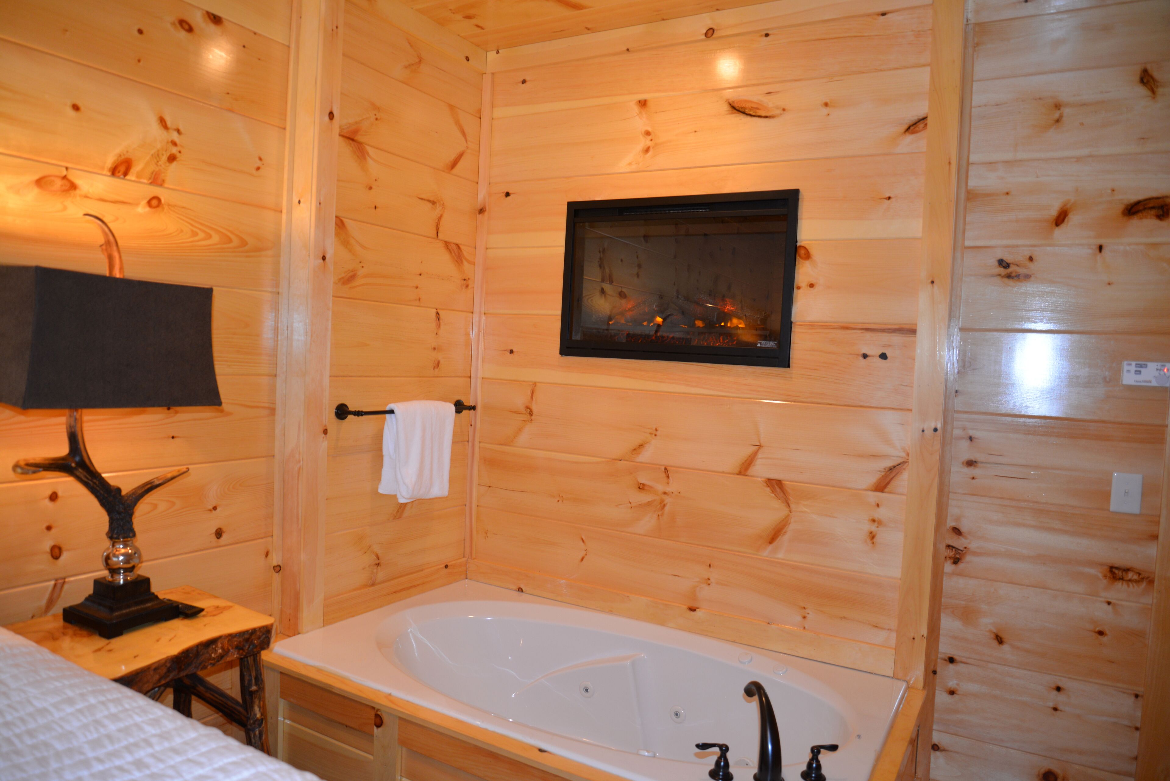 A wooden cabin bathroom with a bathtub, a mirror, and a fireplace.