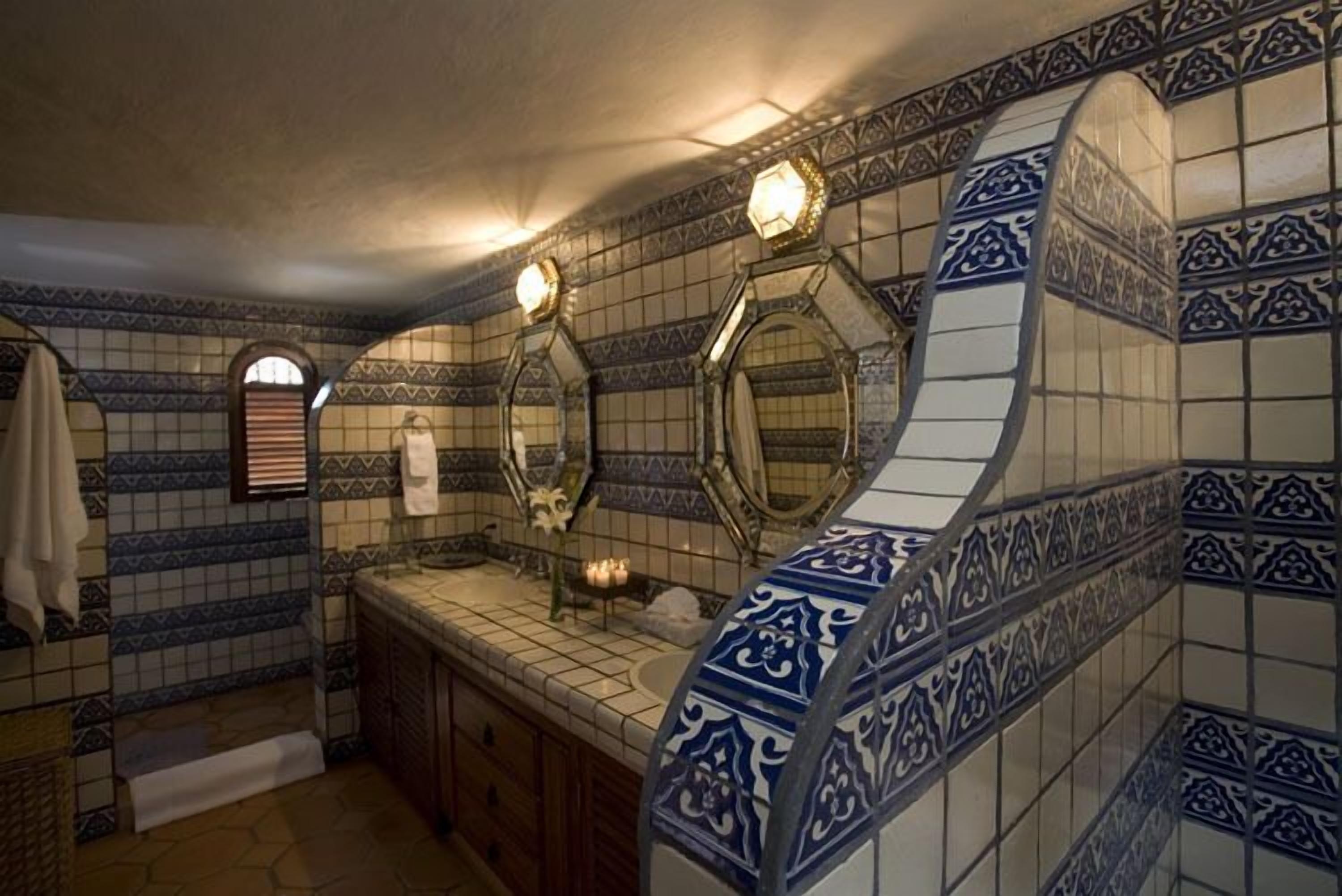 A bathroom with a tiled backsplash, a sink, and two mirrors.