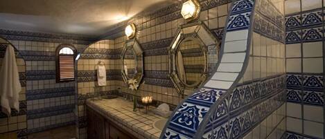 A bathroom with a tiled backsplash, a sink, and two mirrors.