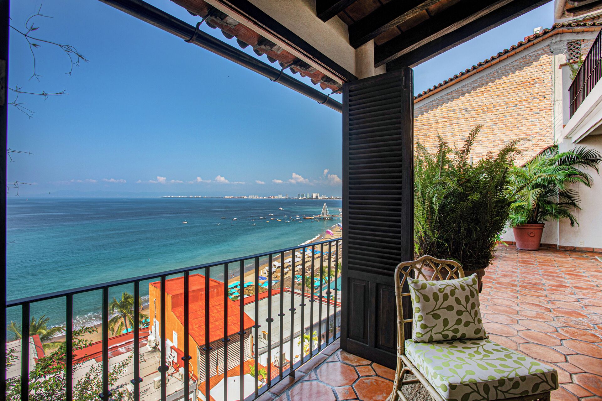 Un balcon avec vue sur la mer, une chaise et une plante en pot.