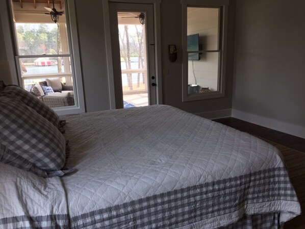 A bedroom with a large bed, a door leading to a balcony, and a window with a view of the outside.