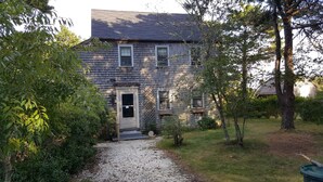Een twee verdiepingen tellend huis met een grindpad dat leidt naar een houten deur.