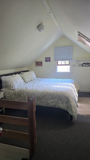 Ein Schlafzimmer mit einem Bett, einem Fenster, einer Wandklimaanlage und einem Deckenlüfter.