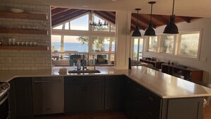 Eine moderne Küche mit einer großen Kochinsel, integrierten Geräten und Blick auf das Meer.