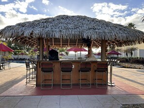 A thatched-roof outdoor bar area with seating and umbrellas. - 4BR/3BA townhouse - Regal Palms, Lazy River - Recommended by Our Son. Nr Disney (Davenport)