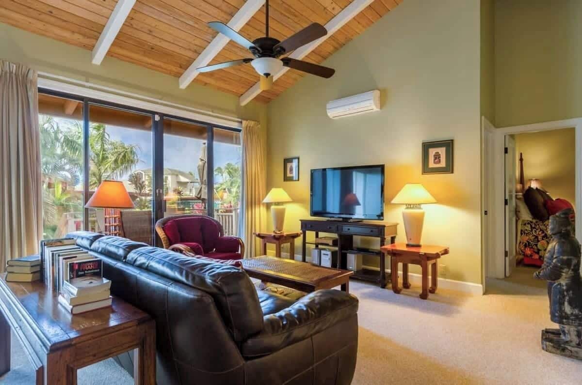 A living room with a leather sofa, a television, and two lamps.