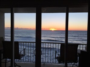 Un balcon avec vue sur l’océan au coucher du soleil.