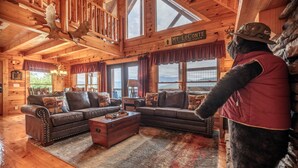 L’intérieur d’une cabane en rondins, avec un grand canapé, une malle en bois et une pancarte indiquant « MT. LECONTE ».