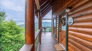 Une cabane en bois dotée d’un balcon donnant sur une zone montagneuse boisée.