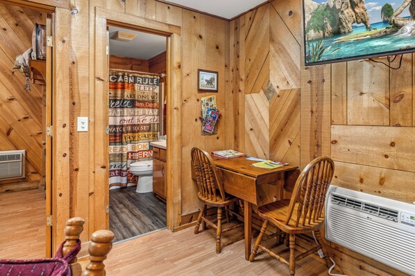 Un interior de madera con una mesa de comedor, sillas, un televisor y una cortina de ducha con diversas frases.