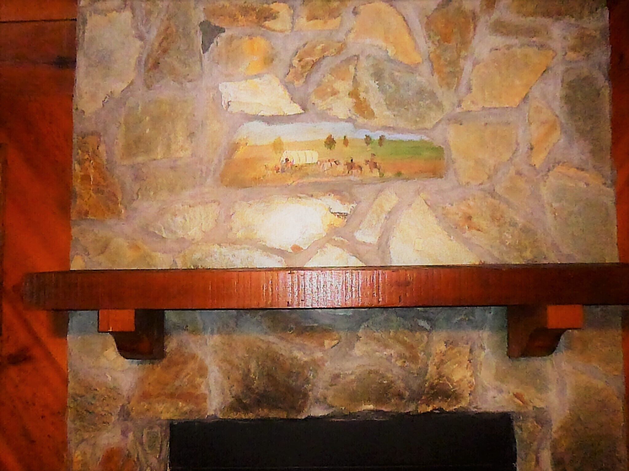 A stone fireplace with a built-in painting of a landscape scene.