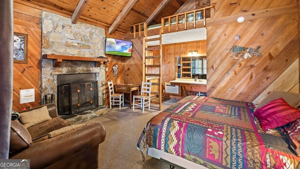 Una cabaña acogedora con chimenea de piedra, un dormitorio en loft y un espacio para escritorio.