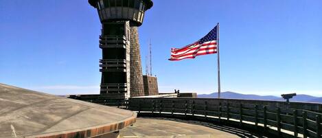 A control tower with an American flag, a clear sky, and mountains in the background.