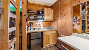 Una cocina compacta con armarios de madera, un refrigerador, un microondas y una estufa.