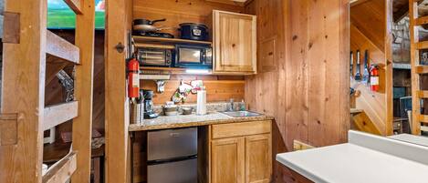 Una cocina compacta con armarios de madera, un refrigerador, un microondas y una estufa.