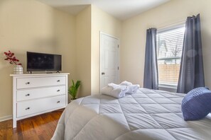 A bedroom with a bed, a TV on a dresser, a door, and a window with curtains. - Close to Downtown, Midtown, GT, GWCC and Mercedes-Benz Stadium (Atlanta)