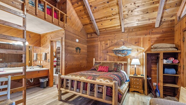 Un dormitorio acogedor estilo cabaña, con cama de madera, un escritorio y una silla.
