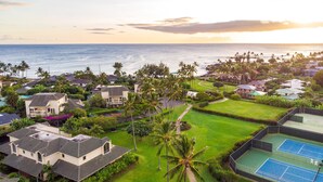 A residential area with houses, a tennis court, and a view of the ocean.