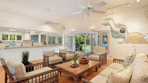 A spacious living area with wicker furniture, a wooden coffee table, and a ceiling fan.