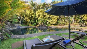 A poolside area with lounge chairs, a table, and an umbrella.