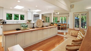A spacious kitchen with a central island, wooden flooring, and a dining area with a sofa and table.