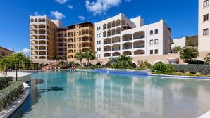 Un hotel con varias edificaciones, piscina y palmeras.