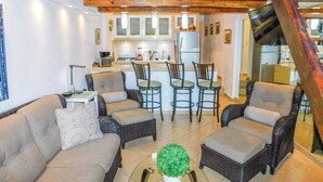 A cozy living room with a sofa, armchairs, and a coffee table. A kitchen with bar stools and a refrigerator is visible in the background. - Boana Torre Malibu #004 , Pool view, romantic zone (Amapas)