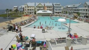 Un resort con una piscina grande, acceso a la playa y varias edificaciones con balcones.