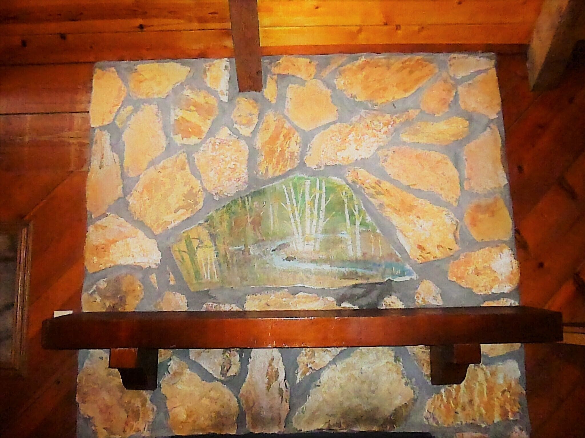 A stone fireplace with a painted landscape mural.