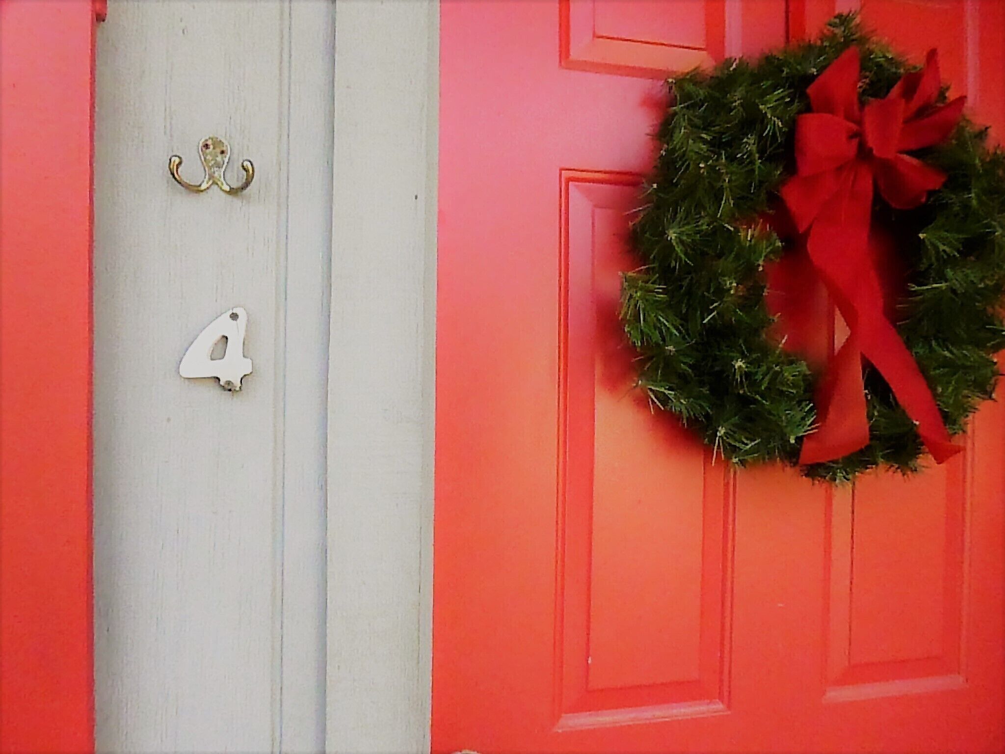A red door with a white number '4' and a wreath with a red ribbon.