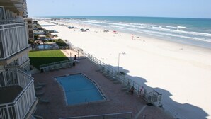 Un hotel con piscina, vista a la playa y un muelle al fondo.