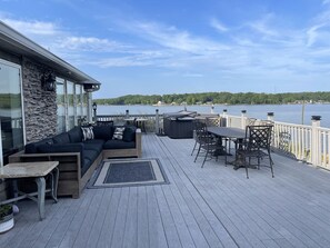 En terrass med en soffa, bord och stolar, med utsikt över en sjö.