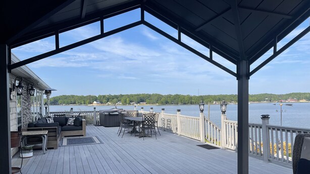 A covered deck with outdoor furniture, a hot tub, and a view of a lake. - Luxury Lakefront Estate! 6BR 4.5BA, Private Dock,Ramp, Lakeside Firepit & More! (Greenwood)